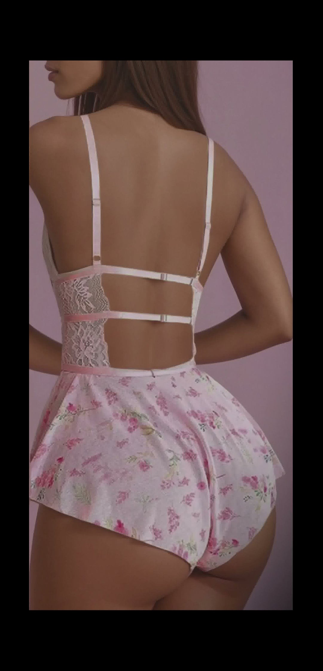 Woman wearing a floral dress with a lace bodice against a pink background
